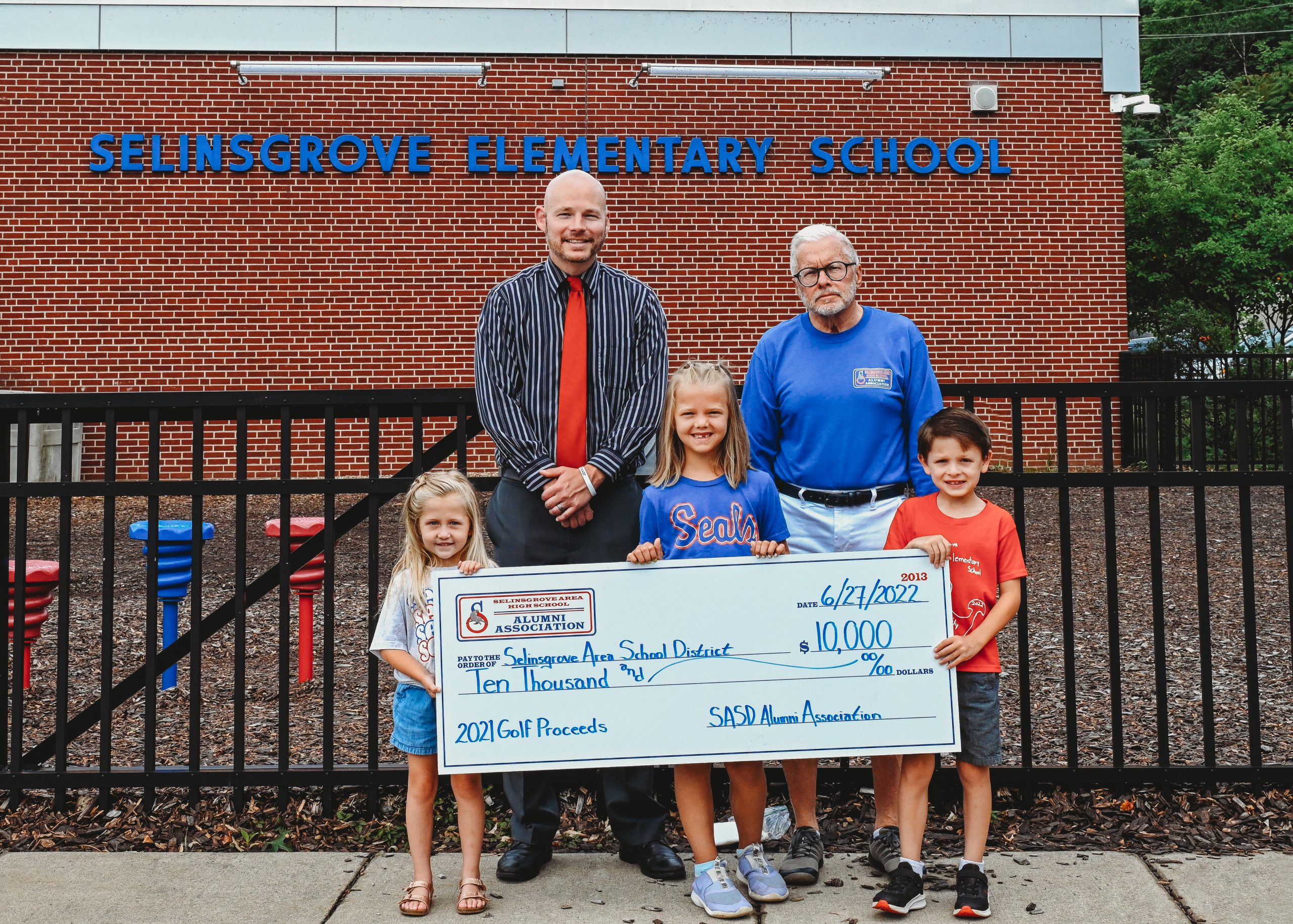 SASD Alumni Association presents check to SASD for $10,000 from the proceeds of the 2021 golf tournament. Back row (left to right) – Mr. Damian Gessel (SAES Principal), Mr. Eric Rowe (SAHS Alumni Association President) Front row (left to right) – Cora Lerch (Kindergarten), Aubrie Hauck (2nd Grade), and Greyson Carr (1st Grade)